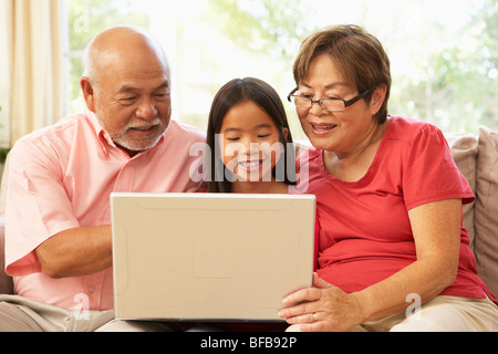 Les grands-parents et petite-fille à l'aide d'un ordinateur portable à la maison Banque D'Images