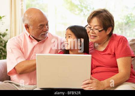 Les grands-parents et petite-fille à l'aide d'un ordinateur portable à la maison Banque D'Images