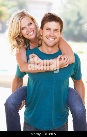 Young Man Giving Woman Piggyback Outdoors Banque D'Images