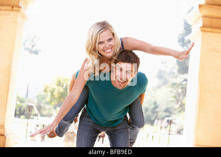 Young Man Giving Woman Piggyback Outdoors Banque D'Images