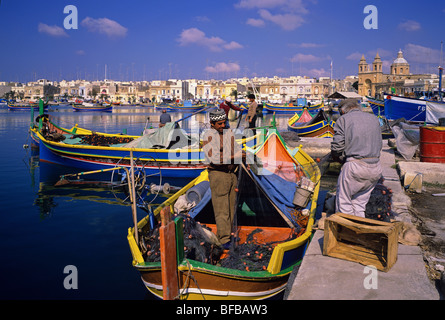 Filets de pêcheurs réparer sur le quai du pittoresque port de pêche de Marsaxlokk Banque D'Images