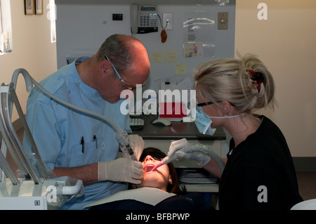 Dentiste et assistante dentaire travaillant sur un jeune patient en chirurgie dentaire moderne Banque D'Images