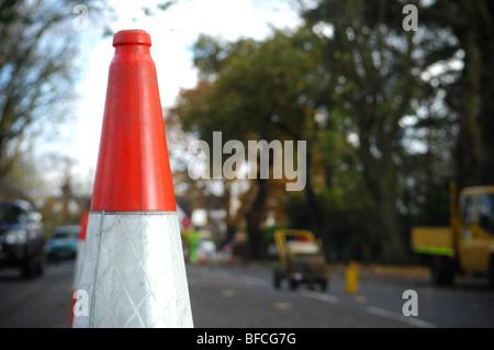 Un cône de circulation rouge et blanc placé au milieu d'une route alors qu'au Royaume-Uni l'entretien de routine est effectué. Banque D'Images