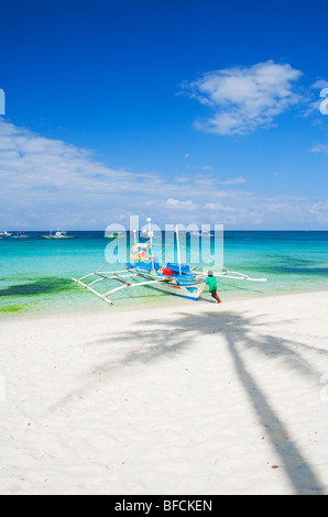 Bateau poussant l'homme à la mer et l'ombre de palmier ; Boracay, Philippines dans les Visayas. Banque D'Images