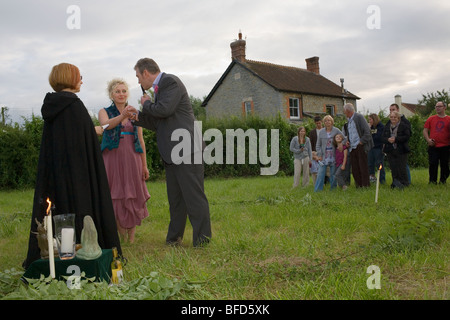 Une sorcière dans un manteau noir se marie avec un couple dans une cérémonie païenne près de Glastonbury. Banque D'Images