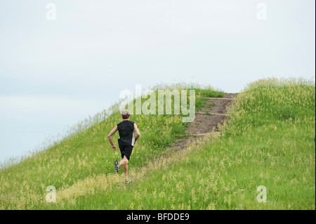 Jeune homme en train d'accumuler la saleté grâce à un sentier au champ vert vif esprit Mound, Dakota du Sud. Banque D'Images