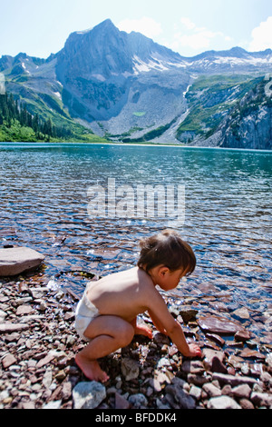 Un garçon de 14 mois joue dans les eaux du lac Snowmass (10,980ft) avec Snowmass montagnes en arrière-plan. Banque D'Images