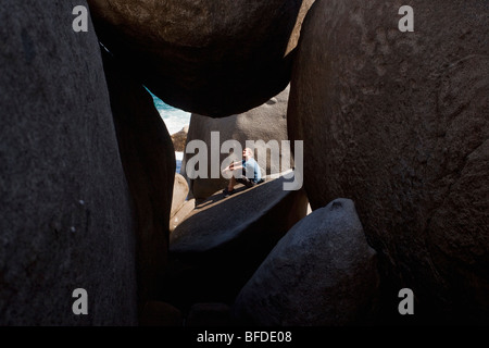 L'homme est assis dans la lumière du soleil à l'extérieur de grotte de rochers géants. Pointe Sud de Virgin Gorda Les Bains Parc national des Îles Vierges Britanniques Banque D'Images