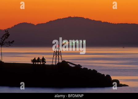 Silhouette de personnes sur un banc de la vue du coucher du soleil, l'Inlet Burrard, Vancouver, British Columbia, Canada Banque D'Images