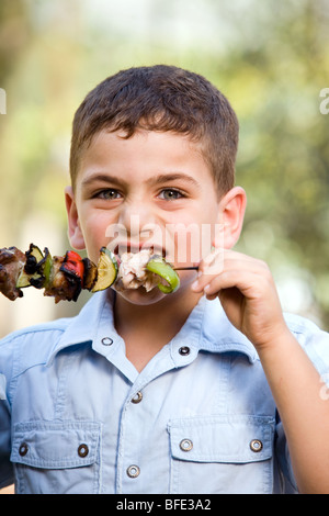 Boy eating une brochette, jour de l'indépendance. Banque D'Images