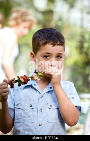 Boy eating une brochette, jour de l'indépendance. Banque D'Images