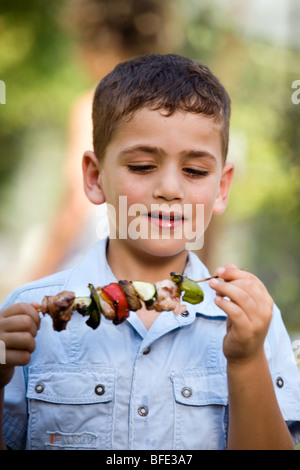 Boy eating une brochette, jour de l'indépendance. Banque D'Images