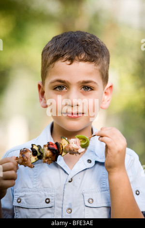 Boy eating une brochette, jour de l'indépendance. Banque D'Images