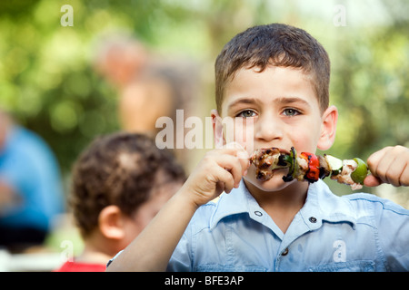 Boy eating une brochette, jour de l'indépendance. Banque D'Images