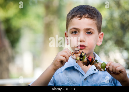 Boy eating une brochette, jour de l'indépendance. Banque D'Images