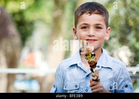 Boy eating une brochette, jour de l'indépendance. Banque D'Images