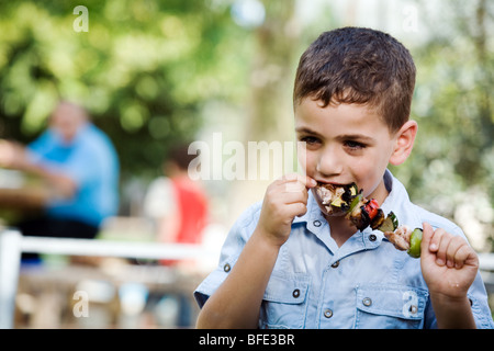 Boy eating une brochette, jour de l'indépendance. Banque D'Images