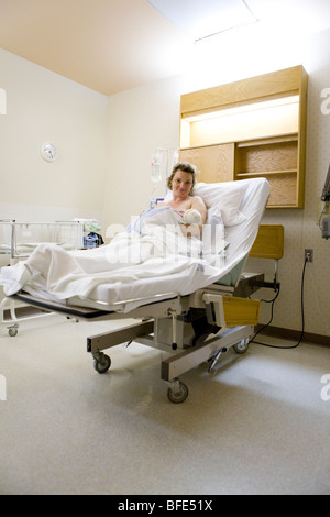 36 ans woman lying in hospital bed avec nouveau-né dans ses bras, Châteauguay, Québec, Canada Banque D'Images