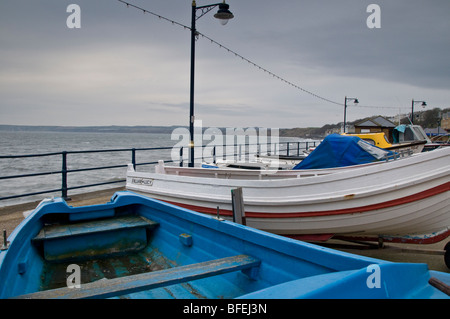 Sur une promenade Filey journée venteuse. Montrant les bateaux de pêche tiré hors de l'eau et sur la mer de défense. Banque D'Images