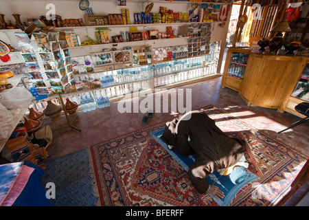 L'homme musulman de prier à l'intérieur de son magasin de souvenirs dans les gorges du Dadès au Maroc Banque D'Images