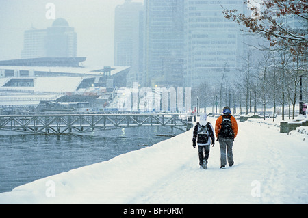 Couple en train de marcher sur la digue du port de charbon dans la neige, Vancouver, British Columbia, Canada Banque D'Images