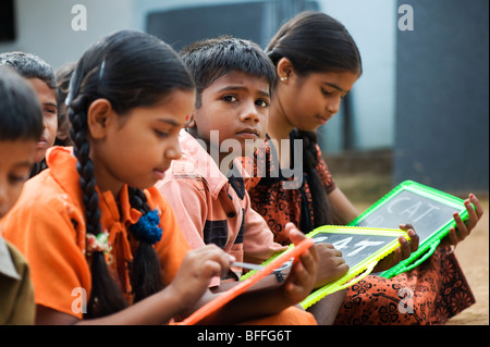 L'école indienne des enfants assis à l'extérieur de l'école écrit sur des tableaux noirs. L'Andhra Pradesh, Inde. Focus sélectif. Banque D'Images