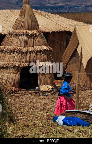 Une femme habitant en face des huttes faites de reed sur l'une des îles flottantes Uros du Lac Titicaca Banque D'Images