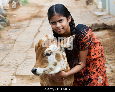 Jeune Indien village girl hugging un veau dans un village de l'Inde rurale. L'Andhra Pradesh, Inde Banque D'Images