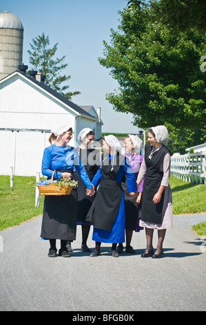 Les jeunes femmes amish amis walking down country lane road, à Lancaster PA les ménagères. Banque D'Images
