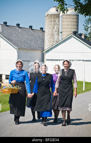 Les jeunes femmes amish amis walking down country lane road, à Lancaster PA les ménagères. Banque D'Images