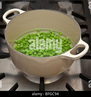 La cuisson de petits pois sur une cuisinière à gaz Banque D'Images