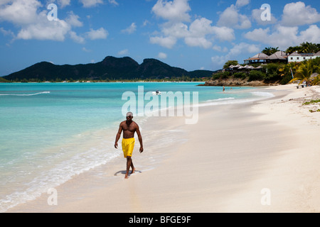 Homme noir marcher le long Ffryes bay, Antigua Banque D'Images