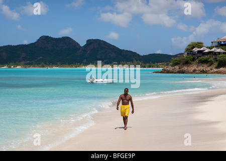 Homme noir marcher le long Ffryes Bay, Antigua Banque D'Images