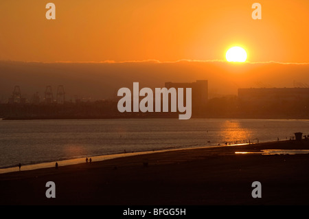 Le port de Long Beach et la plage au coucher du soleil mettant en évidence le contraste entre l'industrie, de l'expédition, les affaires et les loisirs. Banque D'Images