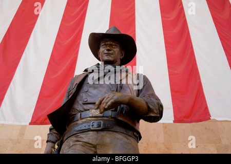 Statue de John Wayne devant un drapeau américain situé dans le terminal de l'aéroport John Wayne dans le comté d'Orange, CA Banque D'Images