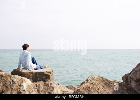 Homme assis sur un rocher surplombant le lac Ontario, Ontario Banque D'Images