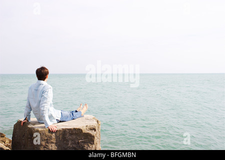 Homme assis sur un rocher surplombant le lac Ontario, Ontario Banque D'Images