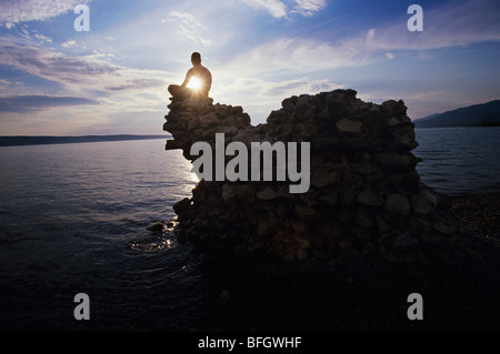 Homme assis sur un rocher surplombant Ocean Banque D'Images