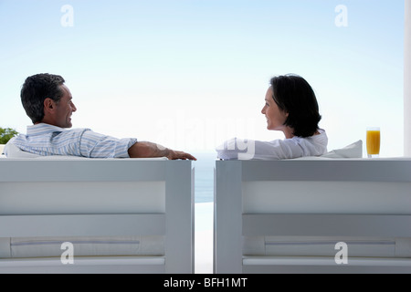 Couple talking, assis sur des chaises longues, à l'extérieur Banque D'Images