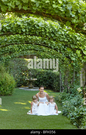 Deux jeunes filles et young bride accroupis sous ivy arches, portrait Banque D'Images