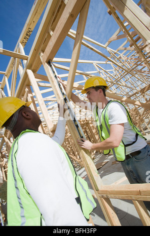 Deux travailleurs de la construction du cadre de mesure des capacités Banque D'Images