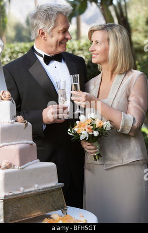 Middle-aged couple toasting près de gâteau de mariage, portrait Banque D'Images