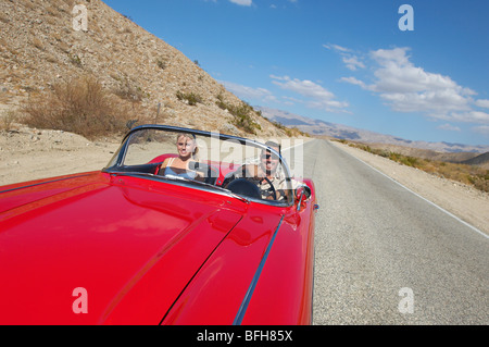 Couple en voiture de collection sur desert road Banque D'Images