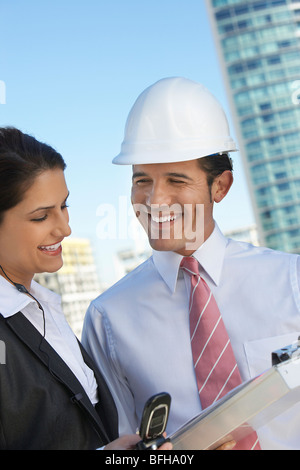 Businessman in hardhat montrant de presse-papiers Banque D'Images