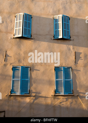 Quatre fenêtres aux volets bleus sur un mur. Banque D'Images