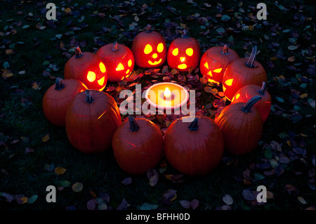 Les citrouilles sculptées dans un cercle au crépuscule autour d'une tarte à la citrouille le soir de l'Halloween Banque D'Images