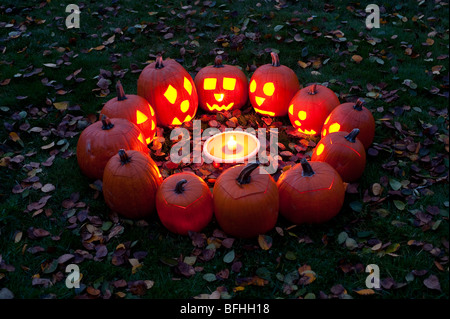 Les citrouilles sculptées dans un cercle au crépuscule autour d'une tarte à la citrouille le soir de l'Halloween Banque D'Images