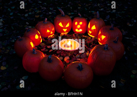 Les citrouilles sculptées dans un cercle au crépuscule autour d'une tarte à la citrouille le soir de l'Halloween Banque D'Images