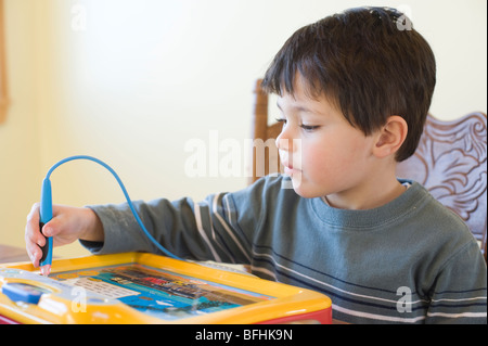 Quatre ans Hispanic boy joue avec un 'Vtec' marque Thomas et ses amis jouet électronique interactif. Modèle droit est libéré. Banque D'Images