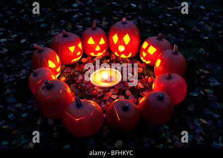 Les citrouilles sculptées dans un cercle au crépuscule autour d'une tarte à la citrouille le soir de l'Halloween Banque D'Images